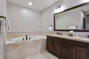 A bathroom with a large sink, a bathtub, and a mirror. There are towels hanging on a rack and a bottle of hand soap on the counter. - Arrowleaf Lodge - Two Bedroom Condo #401 by Deer Valley Resort (Park City)