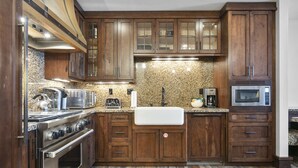 Una cocina con armarios de madera, estufa de acero inoxidable y encimeras de granito.