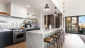 A modern kitchen with a central island, bar stools, and a large window offering a view of the outdoors. - Tower Villas - Five Bedroom Villa w/ Hot Tub #7700 by Deer Valley Resort (Park City)