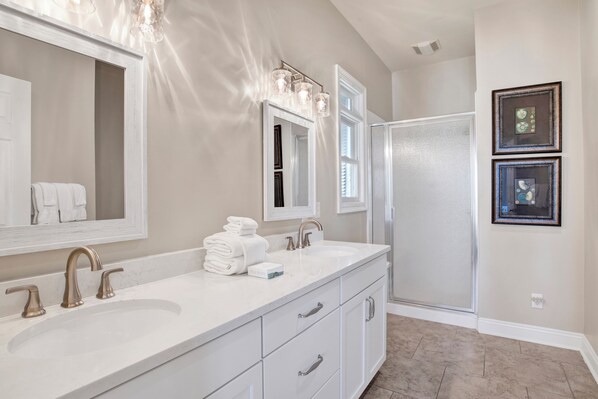 A bathroom with a double sink, a large mirror, and a shower area.