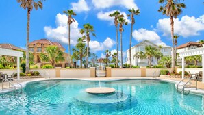 A swimming pool with a fountain, surrounded by palm trees and houses. - Gulf and Lagoon Views | Elevator | Community Pool (Gulf Shores)