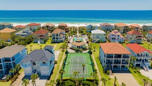 A coastal residential area with beachfront properties, a central swimming pool, and a tennis court. - Gulf and Lagoon Views | Elevator | Community Pool (Gulf Shores)