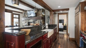 A spacious kitchen with a large island, wooden beams, and a stone fireplace. - Grand Lodge - Three Bedroom Condo #401 - Ski-in/ski-out by Deer Valley Resort (Park City)