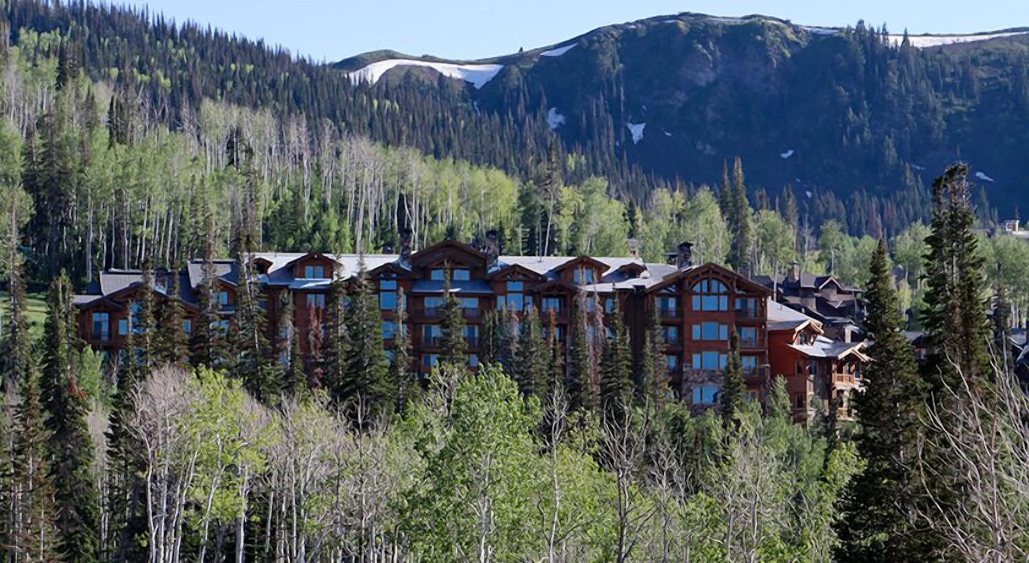 A lodge with multiple wooden buildings surrounded by dense forest and mountains.
