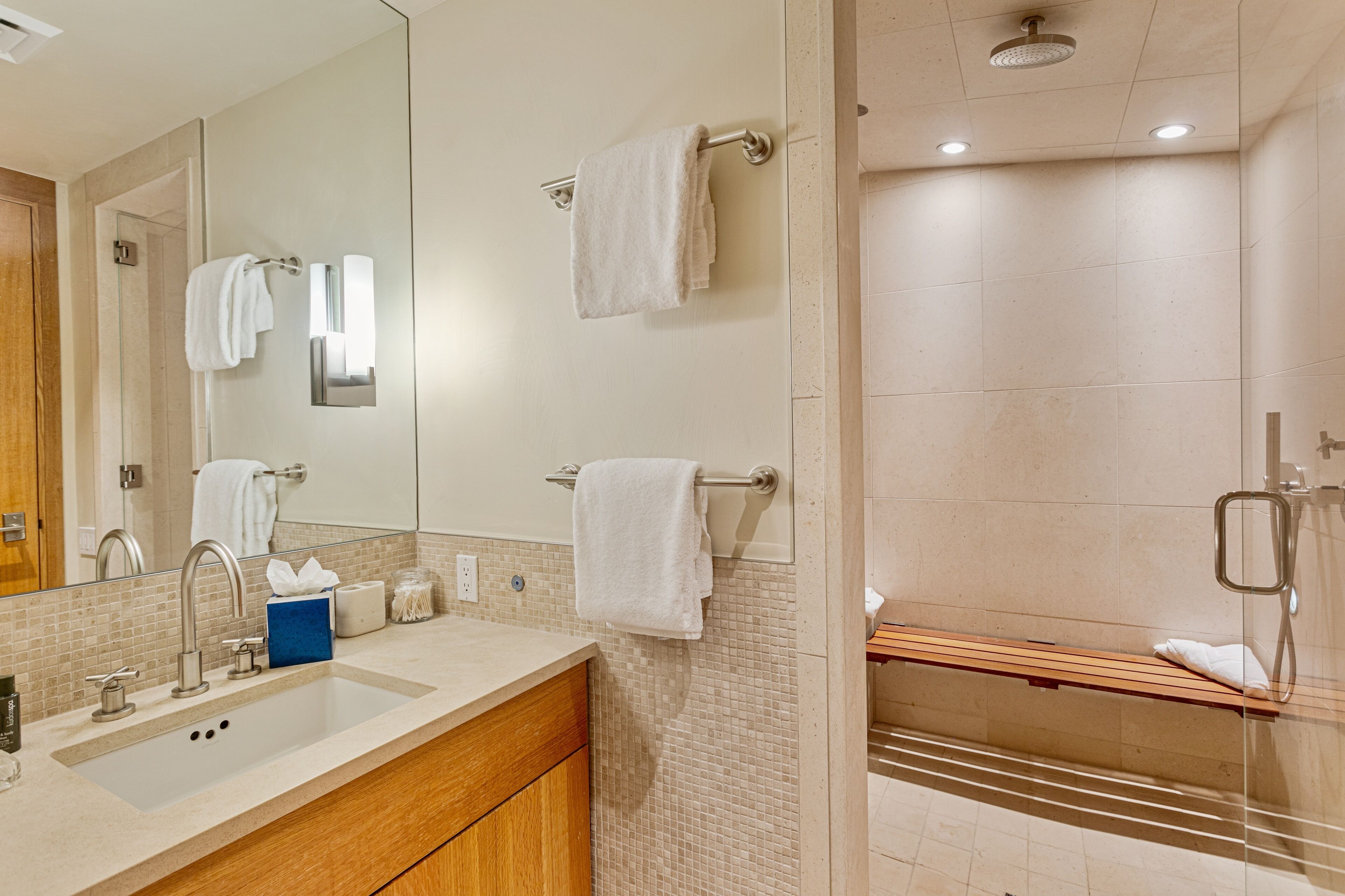 A modern bathroom with a large mirror, a sink, and a shower area.
