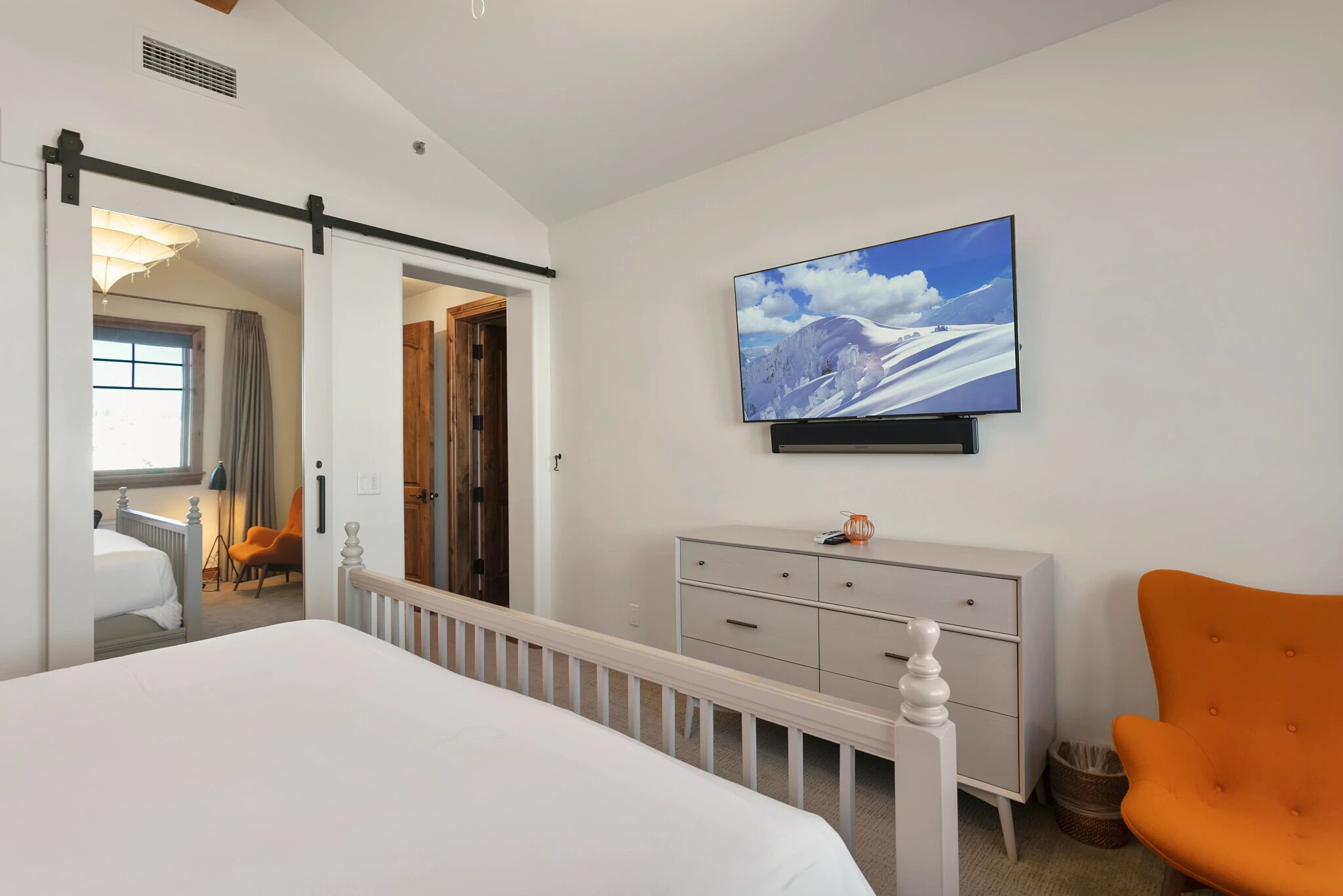A bedroom with a bed, a dresser, a TV, and a chair.
