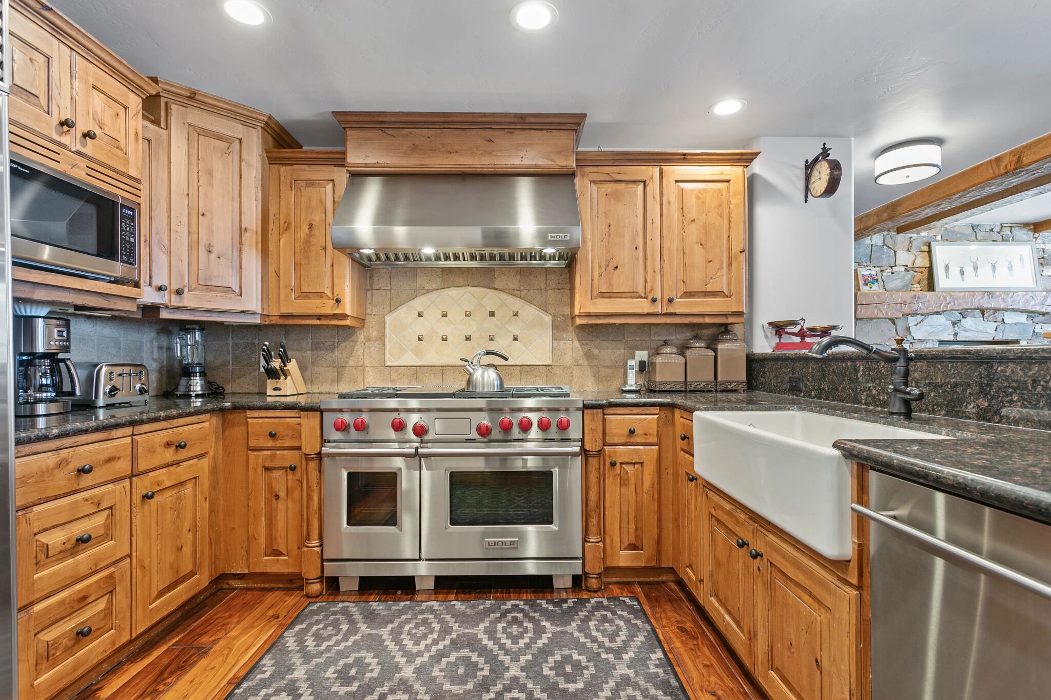 A kitchen with wooden cabinets, stainless steel appliances, a built-in oven, and a stone backsplash.