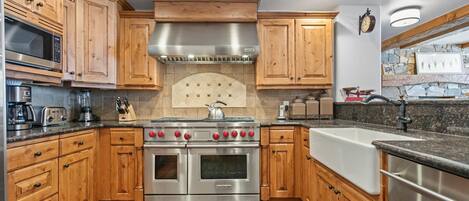 A kitchen with wooden cabinets, stainless steel appliances, a built-in oven, and a stone backsplash.
