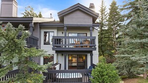 A two-story house with a balcony, a hot tub, and a large evergreen tree in the front yard. - Ridgepoint - Three Bedroom Condo with Spa #128 by Deer Valley Resort (Park City)