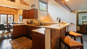 A kitchen with wooden cabinets, a granite countertop, and a built-in island with stools. - Ridgepoint - Three Bedroom Condo with Spa #128 by Deer Valley Resort (Park City)