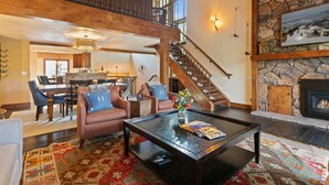 A spacious living area with a high ceiling, a fireplace, and a dining area in the background. - Ridgepoint - Three Bedroom Condo with Spa #128 by Deer Valley Resort (Park City)