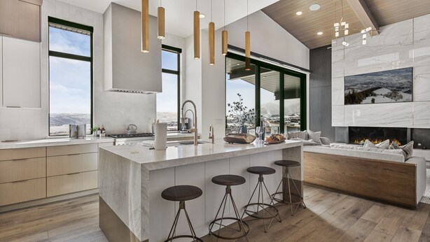 A modern kitchen with a large island, bar stools, and a fireplace.