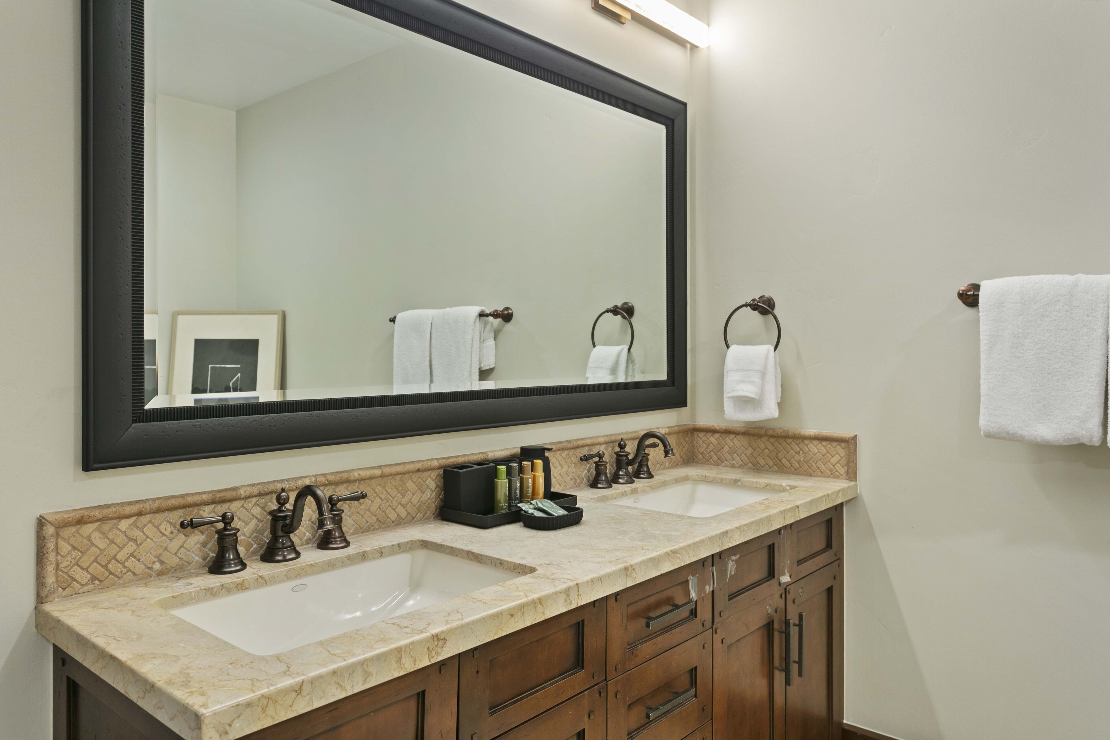A bathroom with a double sink, a large mirror, and wooden cabinets.