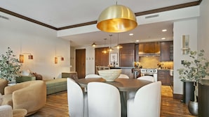 Une cuisine moderne avec des meubles en bois, un grand îlot central doté de chaises et des luminaires suspendus.