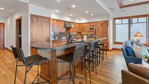 A spacious kitchen with a large island, wooden cabinets, and a bar area with stools. - 305 - Three Bedroom Condo Shooting Star by Deer Valley Resort (Park City)