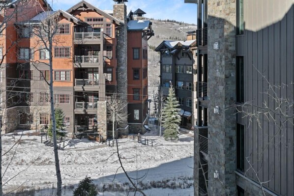 A multi-story building with balconies and a ski slope in the background.