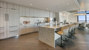 A modern kitchen with a central island, bar stools, and a dining area with a large window. - 201 - Four Bedroom Argent 4 Condo by Deer Valley Resort (Park City)