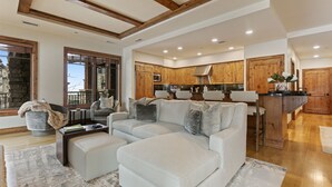 A spacious living room with a large sectional sofa, a coffee table, and a fireplace. The kitchen features wooden cabinets and a central island. - 106 - Three Bedroom Condo Shooting Star by Deer Valley Resort (Park City)