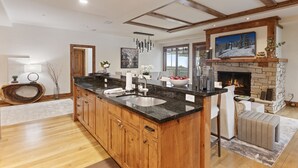 A spacious kitchen with a large island, wooden cabinets, and a stone fireplace. - 106 - Three Bedroom Condo Shooting Star by Deer Valley Resort (Park City)