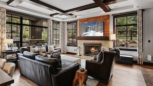 A spacious living room with a fireplace, leather sofas, and large windows offering a view of the outdoors. - 208 - Three Bedroom Condo Flagstaff by Deer Valley Resort (Park City)