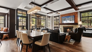 A spacious living area with a fireplace, large windows, and a dining table with chairs. - 208 - Three Bedroom Condo Flagstaff by Deer Valley Resort (Park City)