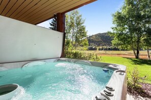 A hot tub with a clear view of a lush green landscape and hills in the background.