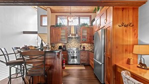 A kitchen with wooden cabinets, a central island, and a dining area with chairs. - 107 - Three Bedroom Condo with Spa Ridgepoint by Deer Valley Resort (Park City)