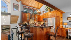 A kitchen with wooden cabinets, a central island with bar stools, a refrigerator, and a hanging light fixture. - 107 - Three Bedroom Condo with Spa Ridgepoint by Deer Valley Resort (Park City)