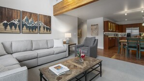 A modern living room with a grey sofa, a wooden coffee table, and a painting of mountains. - 1490 - Three Bedroom Condo with Spa Aspenwood by Deer Valley Resort (Park City)