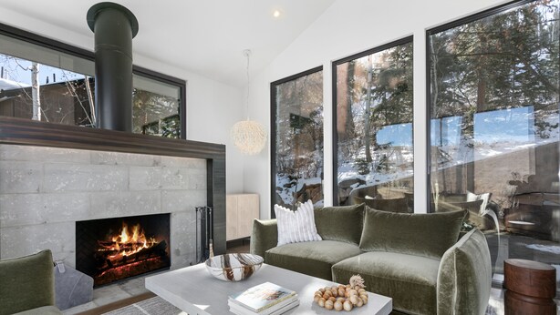 A modern living room with a fireplace, large windows, and a cozy green sofa. - 656 Coalition View Court - 4 Bedroom Private Home With Spa by Deer Valley Resort (Park City)