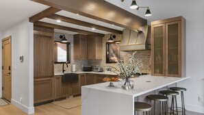 A modern kitchen with wooden cabinets, a marble island, and bar stools. - 1072 - Three Bedroom Condo with Spa Boulder Creek by Deer Valley Resort (Park City)