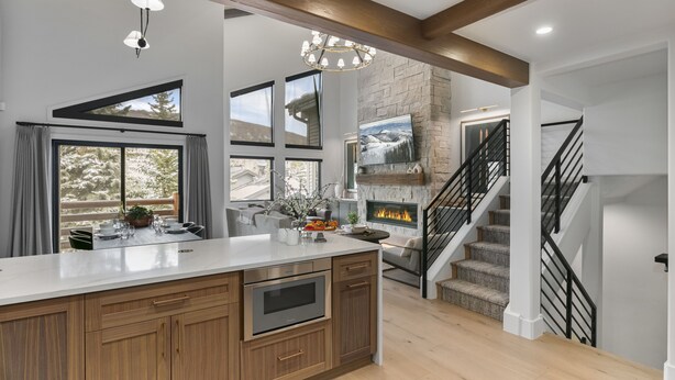 A modern kitchen with a large island, built-in oven, and a fireplace. There is a staircase leading to an upper level. - 1072 - Three Bedroom Condo with Spa Boulder Creek by Deer Valley Resort (Park City)