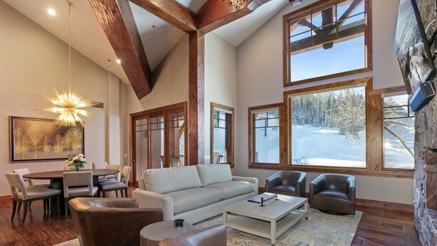 A spacious living room with a large window, a fireplace, and a dining area. - 504 - Five Bedroom Condo Penthouse Grand Lodge by Deer Valley Resort (Park City)