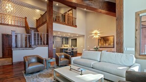 A spacious living area with a staircase, a sofa, a coffee table, and a dining area. - 504 - Five Bedroom Condo Penthouse Grand Lodge by Deer Valley Resort (Park City)