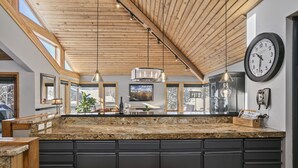 A kitchen with a granite countertop, wooden ceiling beams, and pendant lighting. - 2060 Solamere Drive - Four Bedroom Home by Deer Valley Resort (Park City)