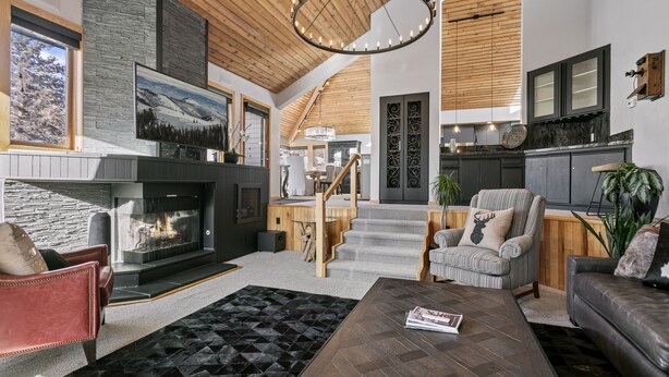 A spacious living area with a fireplace, a herringbone-patterned coffee table, and a striped armchair. - 2060 Solamere Drive - Four Bedroom Home by Deer Valley Resort (Park City)