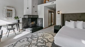 A modern bedroom with a large bed, a fireplace, a desk, and a mirror. - 2060 Solamere Drive - Four Bedroom Home by Deer Valley Resort (Park City)