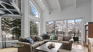 A spacious living room with large windows, a sectional sofa, a coffee table, and a bookshelf. - 1688 - Five Bedroom Condo with Hot Tub Pinnacle by Deer Valley Resort (Park City)