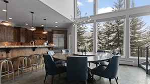 A modern kitchen with a large island, bar stools, and a dining area with a round table and chairs. - 1688 - Five Bedroom Condo with Hot Tub Pinnacle by Deer Valley Resort (Park City)