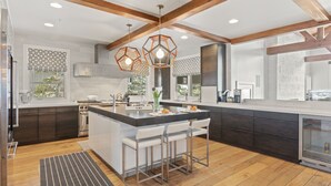 A modern kitchen with a central island, bar stools, pendant lighting, and wooden beams. - 6977 Silver Lake Drive - 5 Bedroom Private Home with Hot Tub by Deer Valley Resort (Park City)