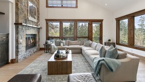 Un salón amplio con chimenea de piedra, ventanas grandes y una zona de estar acogedora.