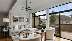 A spacious living room with a sofa, armchairs, a coffee table, and a fireplace.
