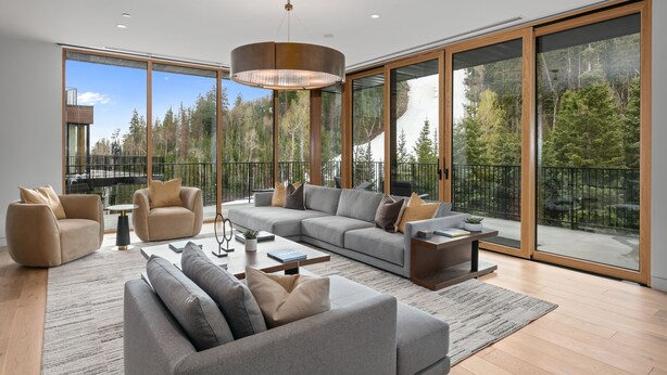 A spacious living room with a large sectional sofa, a coffee table, and a chandelier. - 1504 Founders Place - Three Bedroom Condo Deluxe by Deer Valley Resort (Park City)