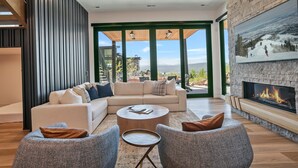 A modern living room with a fireplace, a sectional sofa, and a view of the outdoors. - 1868 W SkyRidge Drive 4 Bedroom Home with Hot Tub by Deer Valley Resort (Heber City)