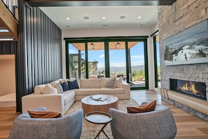 A modern living room with a fireplace, a sectional sofa, and a view of the outdoors.