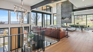 A spacious living area with a fireplace, large windows, and a view of the outdoors. - 1868 W SkyRidge Drive 4 Bedroom Home with Hot Tub by Deer Valley Resort (Heber City)