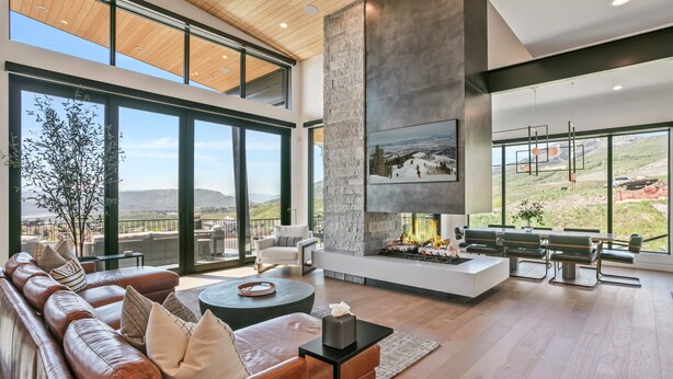 A modern living room with a fireplace, large windows, and a view of the mountains. - 1868 W SkyRidge Drive 4 Bedroom Home with Hot Tub by Deer Valley Resort (Heber City)