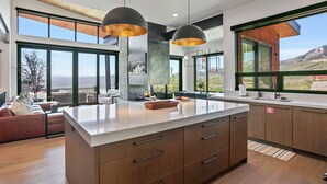 A modern kitchen with large windows, a central island, and a dining area with a view. - 1868 W SkyRidge Drive 4 Bedroom Home with Hot Tub by Deer Valley Resort (Heber City)