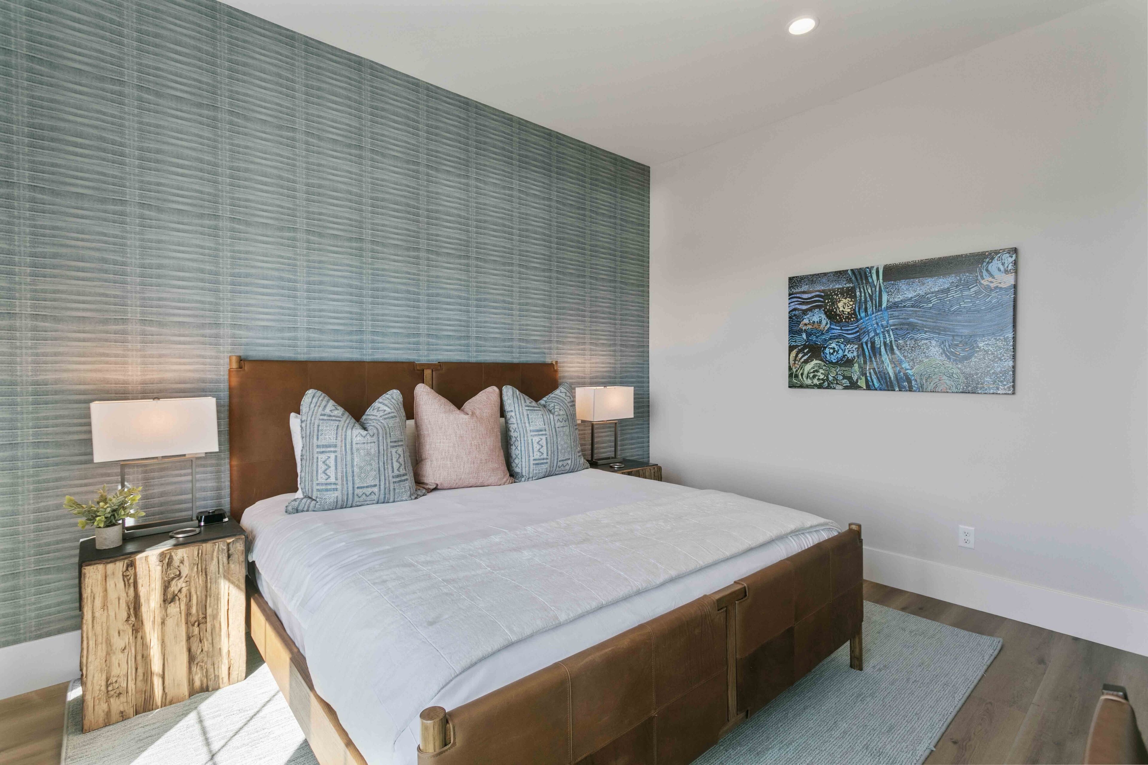 Ein modernes Schlafzimmer mit einem großen Bett, einem Holzkopfende und einem Bild an der Wand.