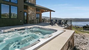 Ein modernes Haus mit Whirlpool und Sitzgelegenheit im Freien mit Blick auf einen See.